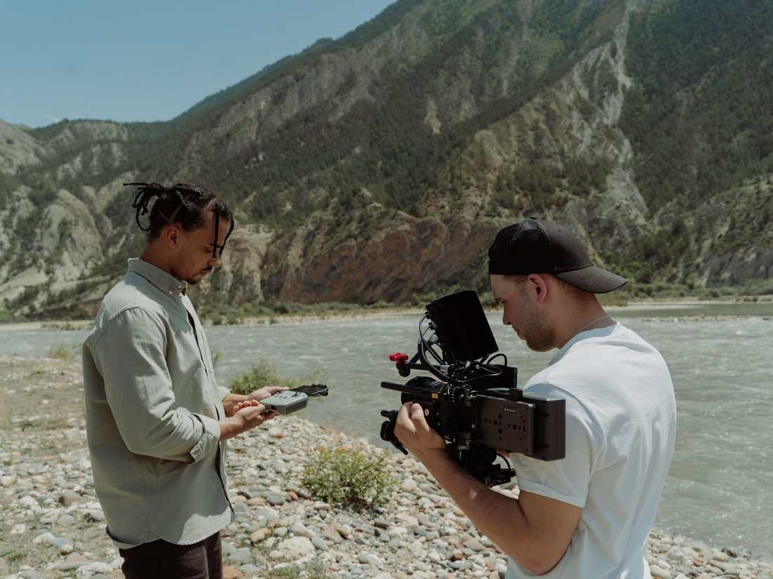 Two filmmakers on location, one operating a cinema camera and one recording sound