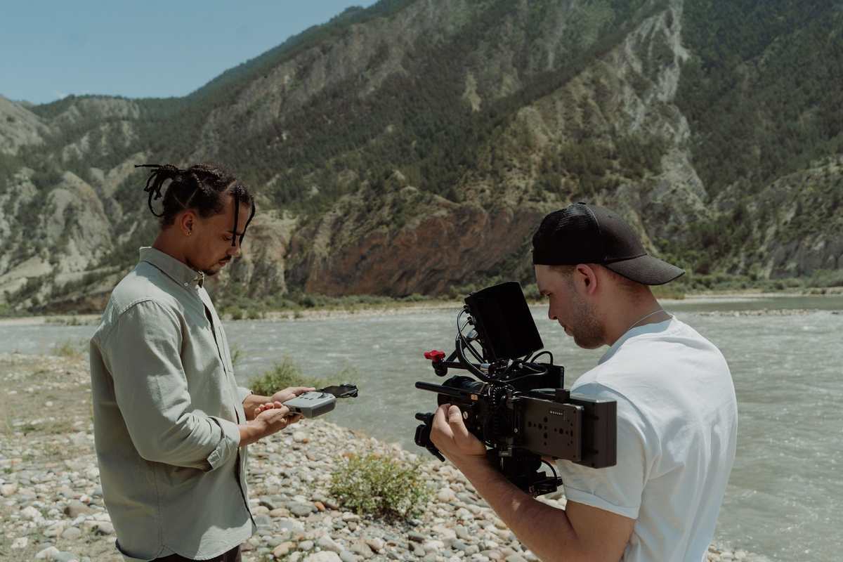 Two filmmakers on location, one operating a cinema camera and one recording sound